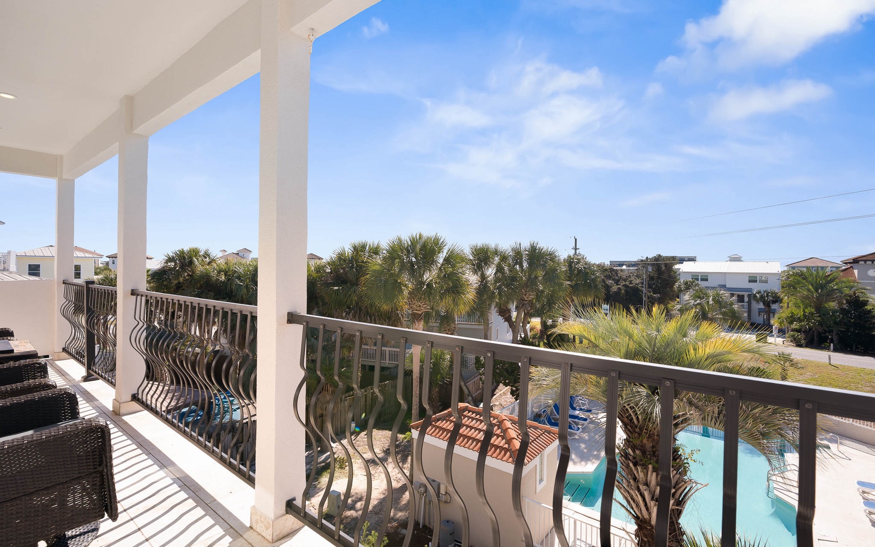 Relax on your private balcony overlooking tropical palms and the sparkling pool below on this perfect sunny day.