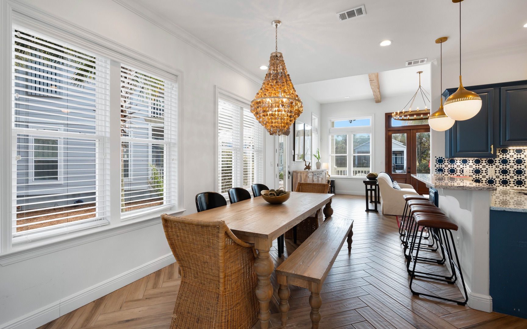 You'll love gathering around this stunning farmhouse table, bathed in natural light from oversized windows while the golden chandelier creates perfect ambiance.