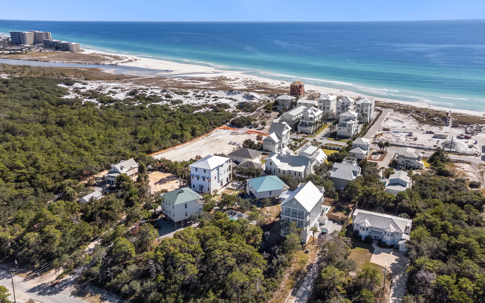 Stunning coastal community nestled between pristine beach and lush natural landscape along crystal-clear emerald waters.