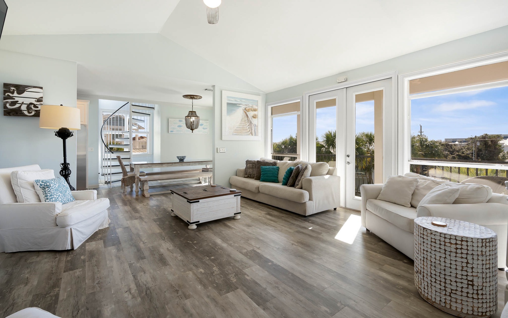 Sink into plush white sofas bathed in natural light, where floor-to-ceiling windows frame peaceful treetop views for your perfect getaway.