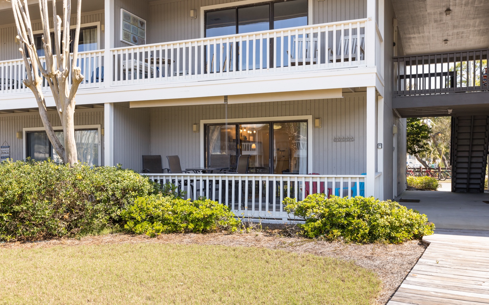 Property building with multi-level balconies and landscaped grounds featuring mature trees and manicured shrubs.