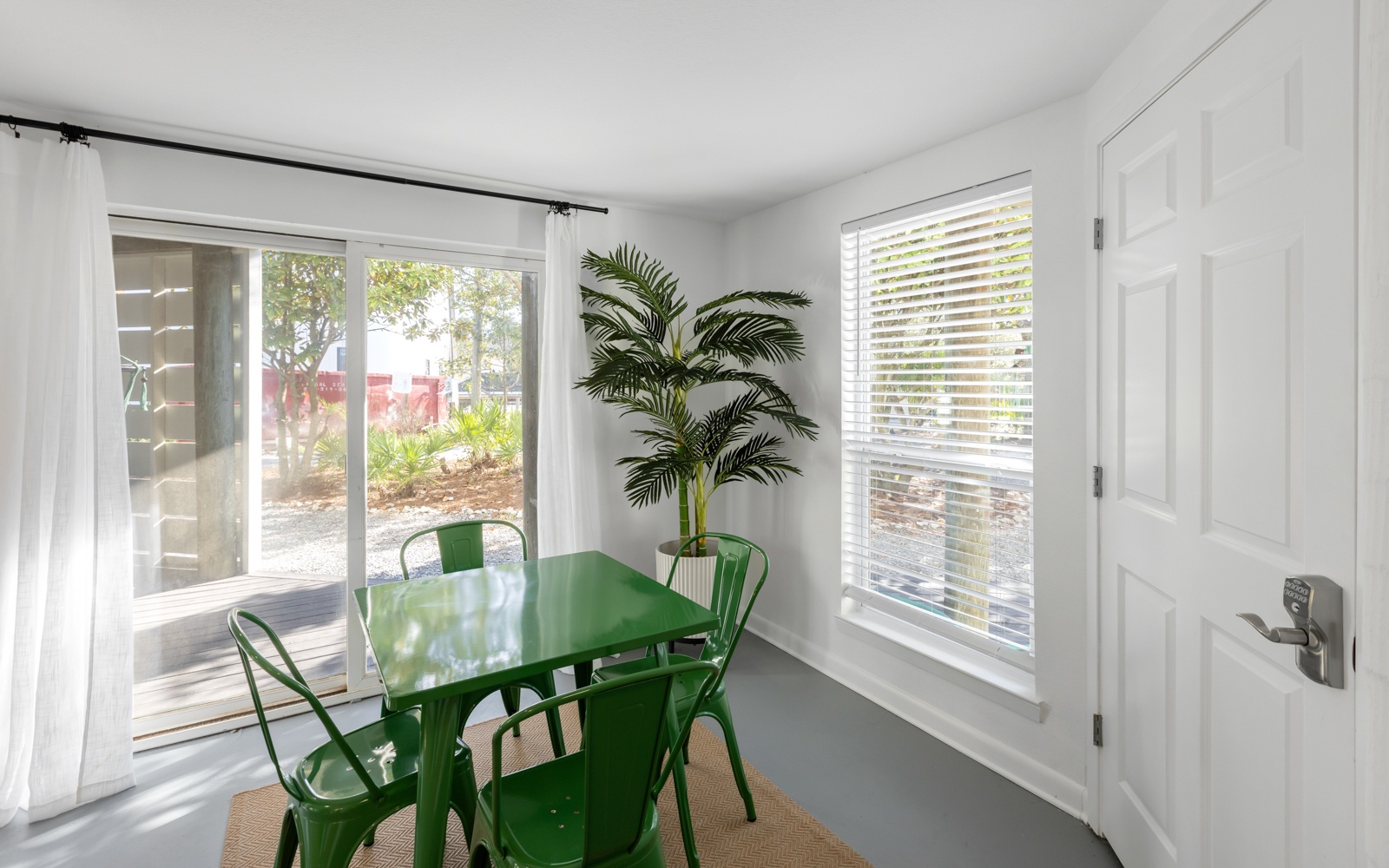 Gather around your bright green dining set where natural light streams through sliding doors, creating the perfect spot for morning coffee.