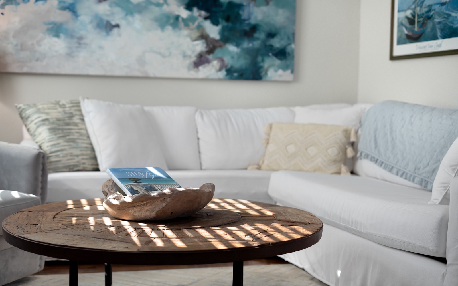 Sink into this plush sectional sofa where natural light creates dancing shadows across the rustic coffee table—your perfect spot for morning coffee and quiet moments.