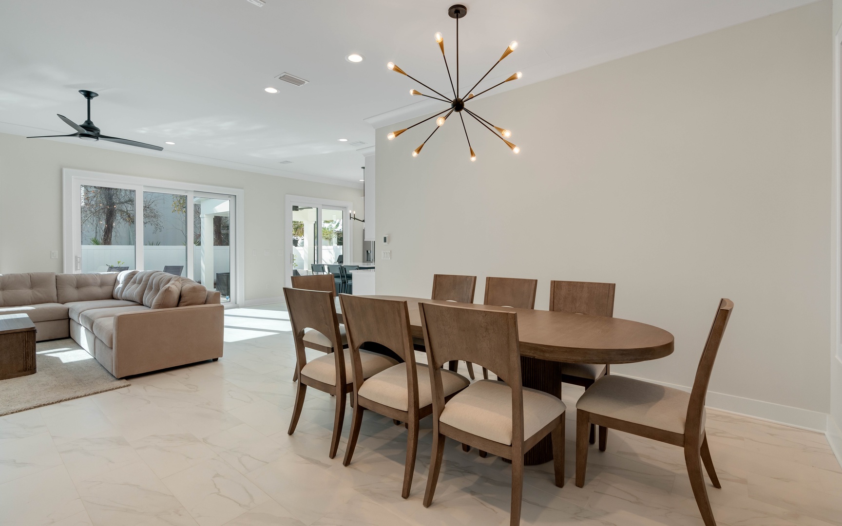 Gather around your elegant dining table for eight, bathed in natural light from floor-to-ceiling windows overlooking the patio.