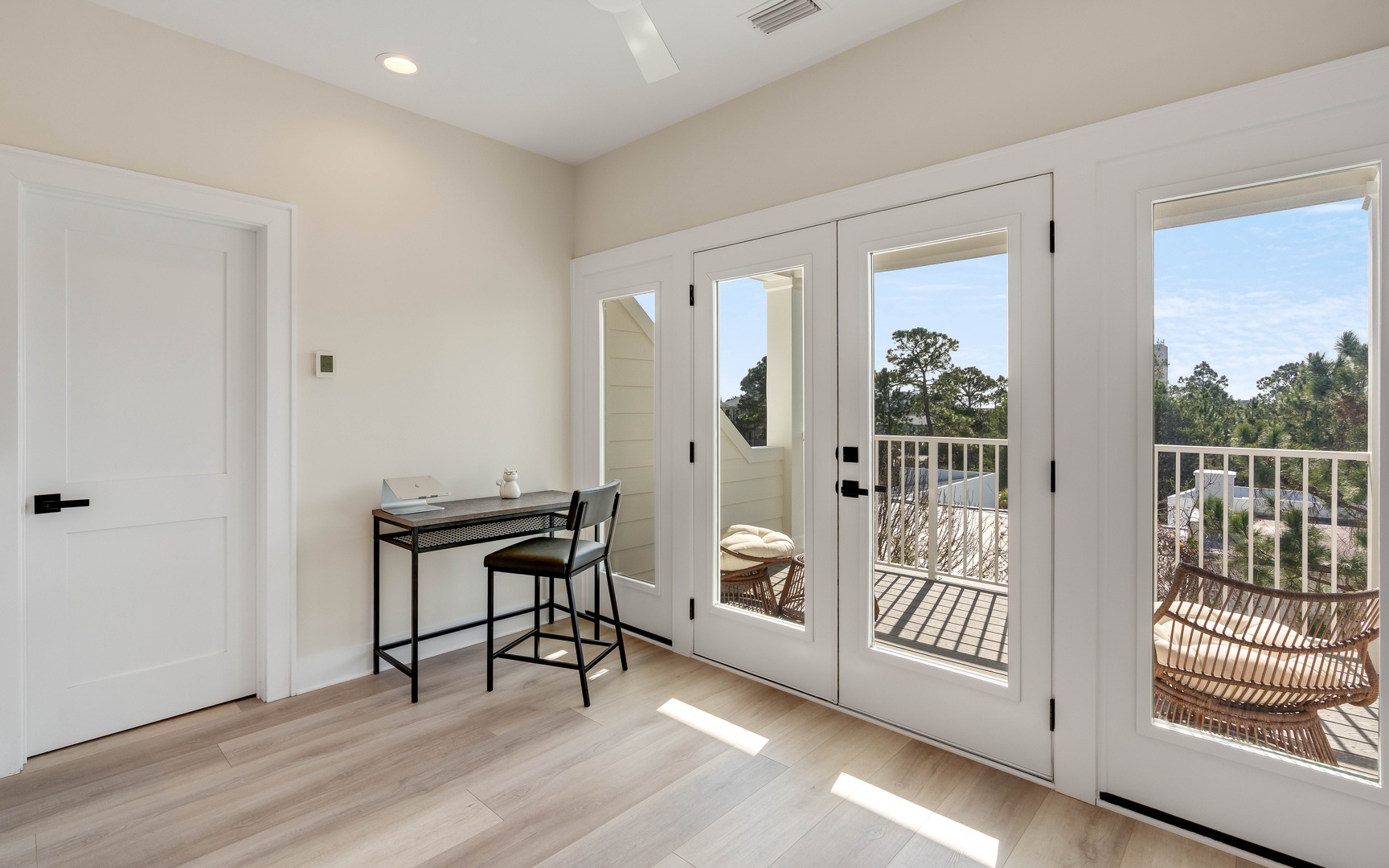 Step into your bright workspace with French doors opening to a private balcony where wicker chairs await your morning coffee moments.