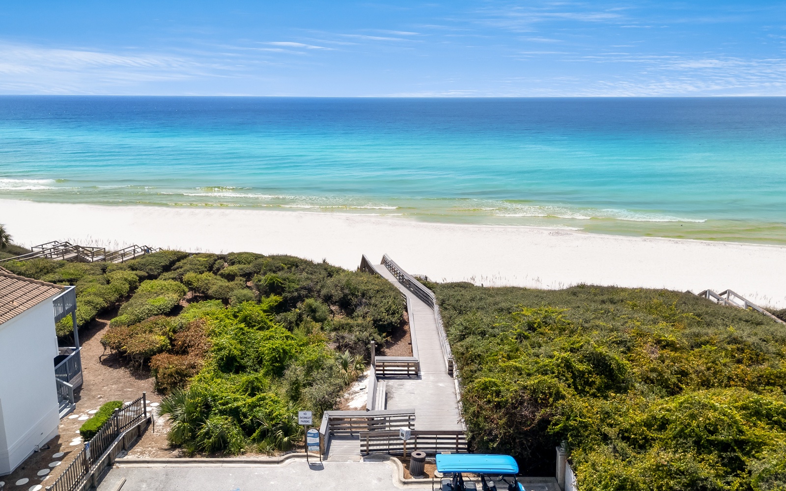 Pristine white sand beach with turquoise waters stretches endlessly, accessed by scenic wooden boardwalks through coastal vegetation.