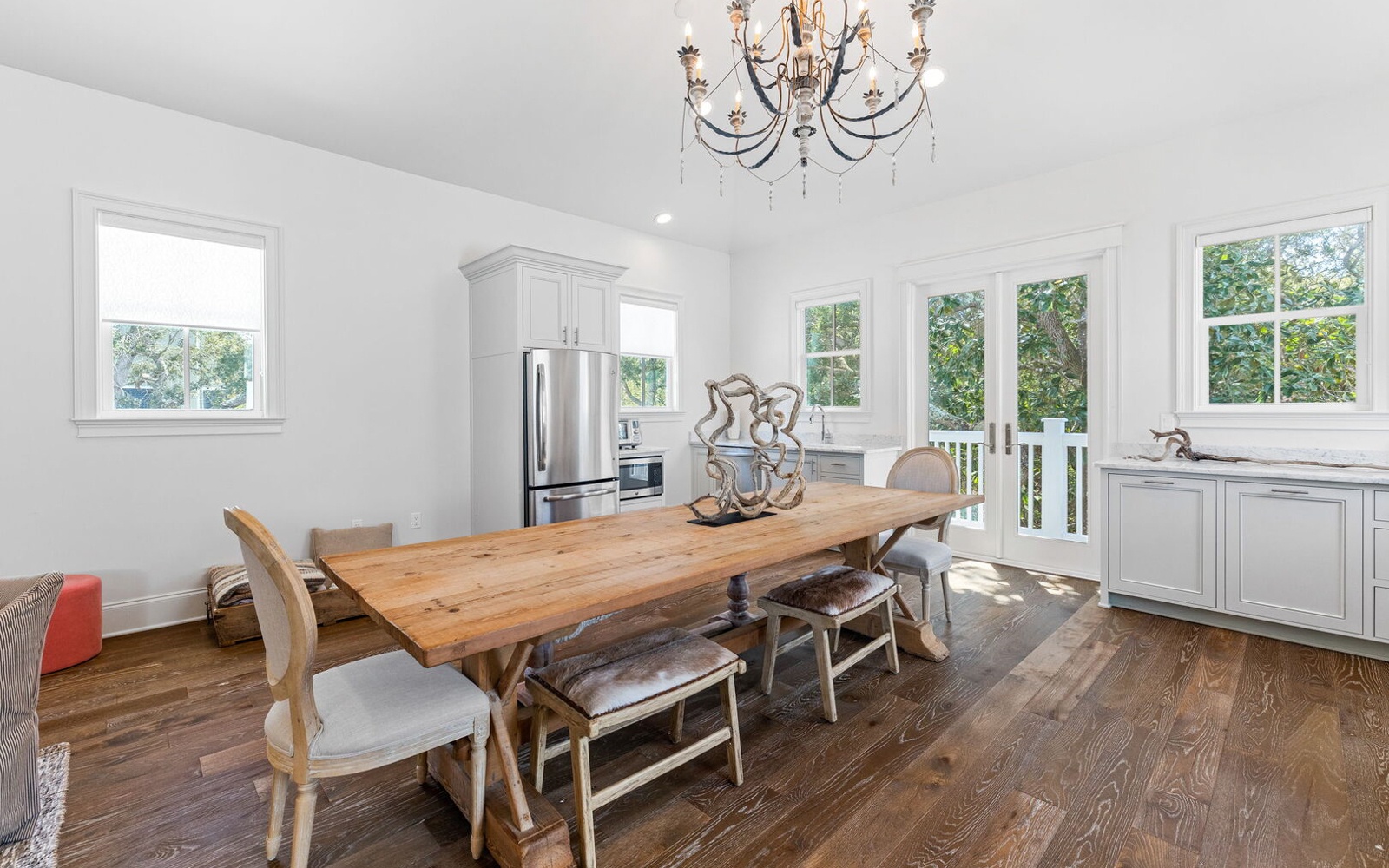 Gather around your elegant dining table under a stunning chandelier, with garden views and modern kitchen nearby for memorable meals.