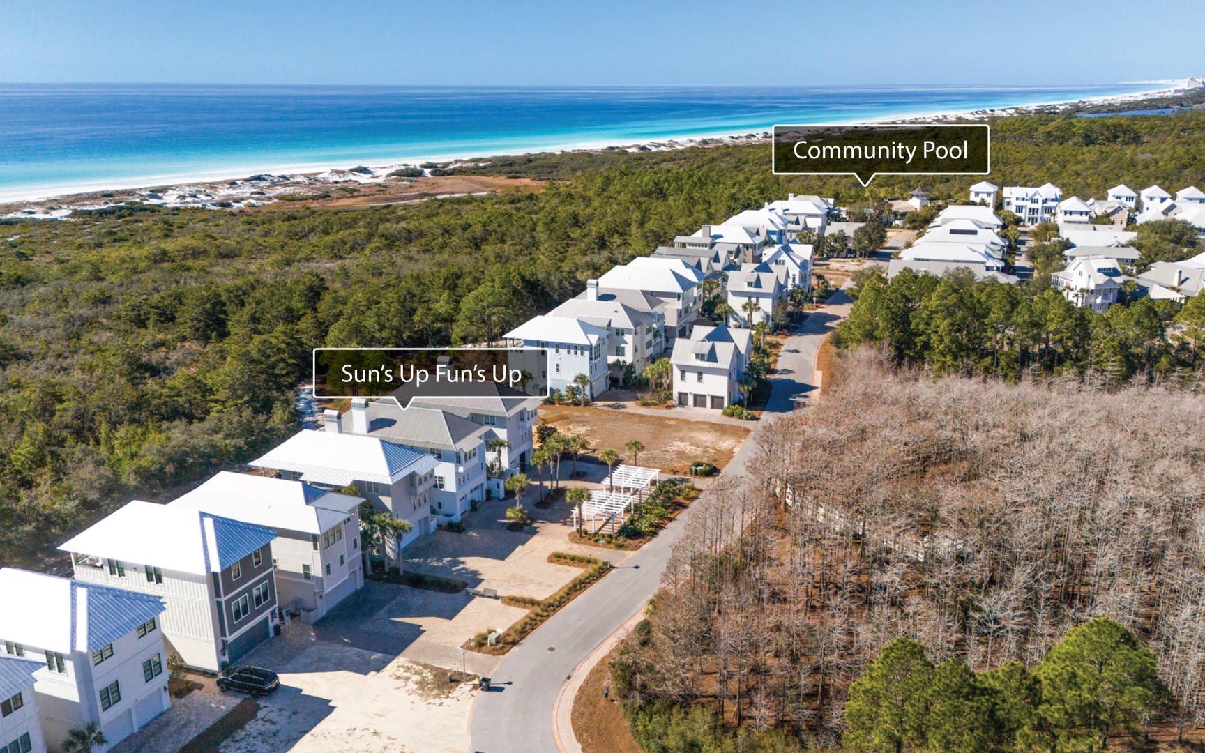 Stunning aerial view of vacation homes nestled between pristine white sand beaches and lush coastal vegetation.