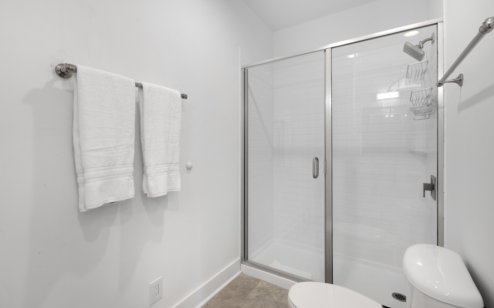 Step into your pristine bathroom featuring a spacious glass-enclosed shower with modern fixtures and fresh towels awaiting your arrival.