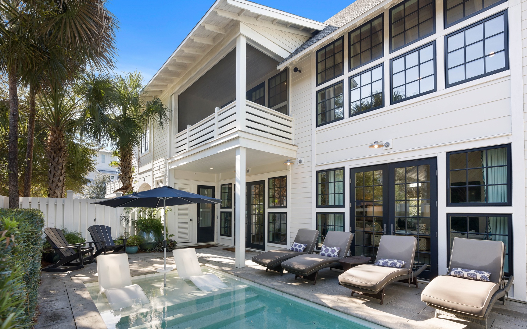 Your private oasis awaits with a sparkling pool, comfortable loungers, and tropical palms creating the perfect sunny retreat.