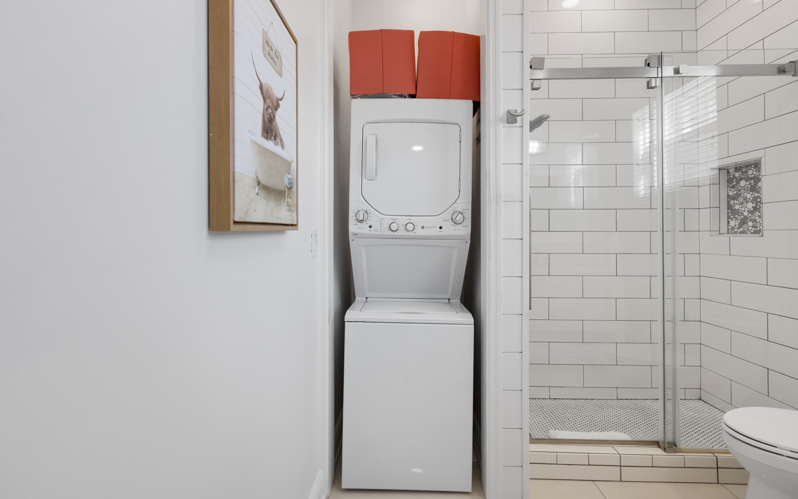 Refresh and recharge in your modern bathroom featuring a convenient washer-dryer combo and sleek glass-enclosed shower.