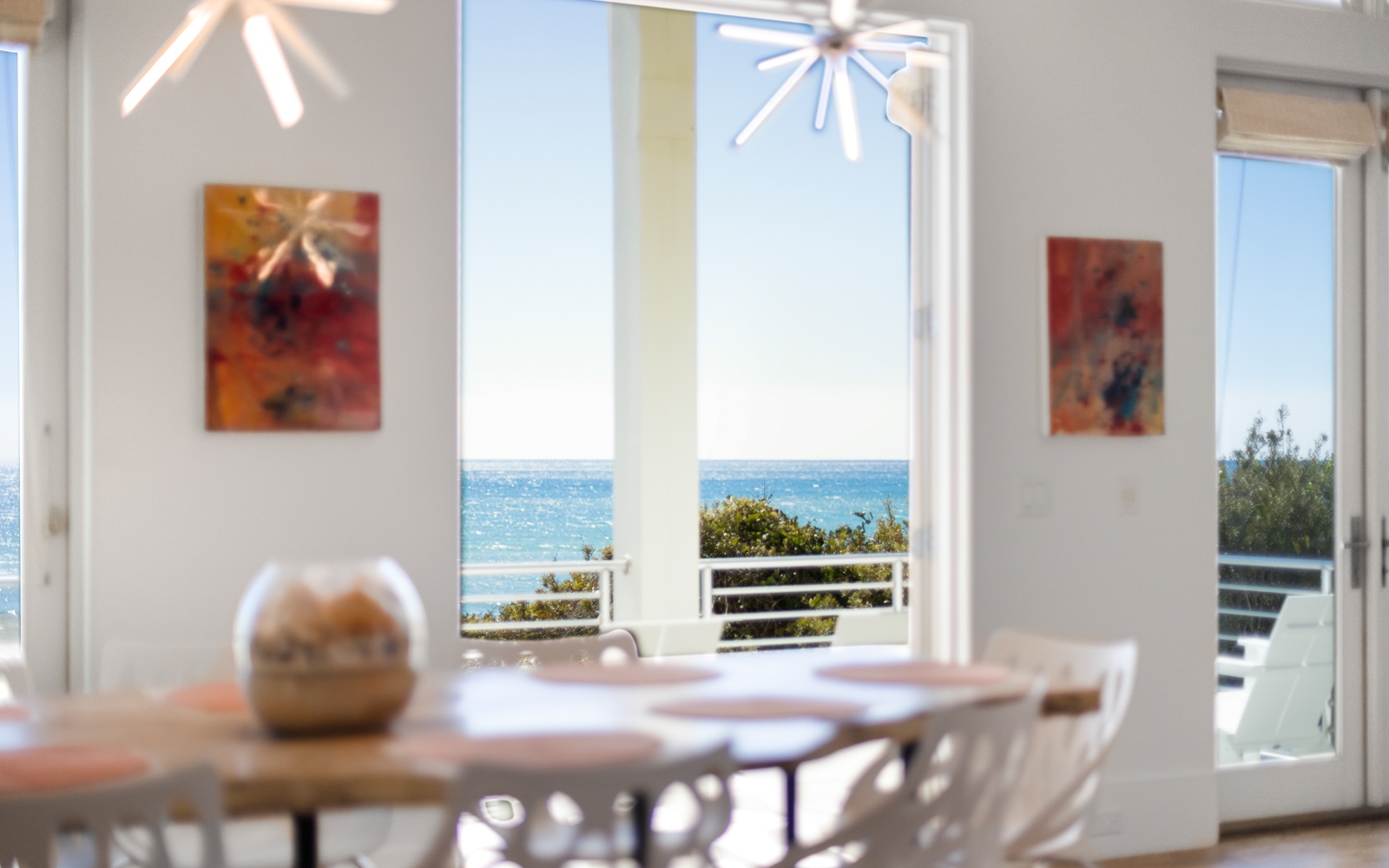 Your dining space opens to breathtaking ocean views through floor-to-ceiling windows, where modern art meets coastal serenity for unforgettable meals.
