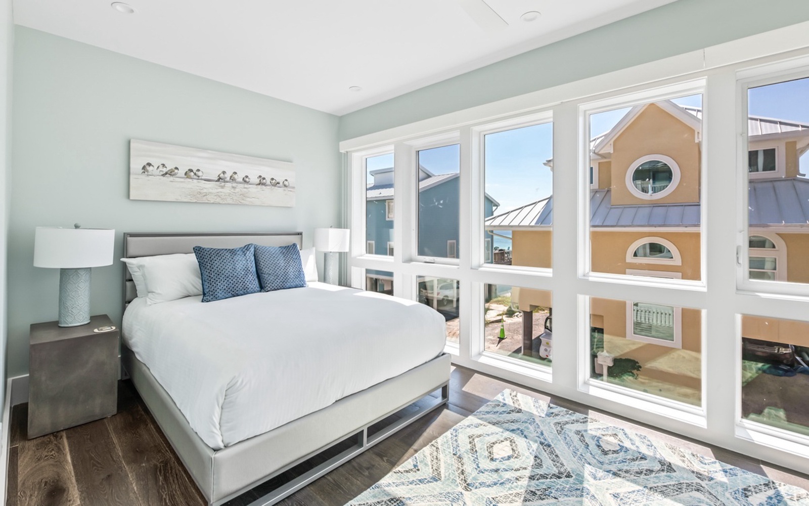 Rest peacefully in your serene bedroom featuring crisp white linens, calming mint walls, and natural light streaming through expansive windows.