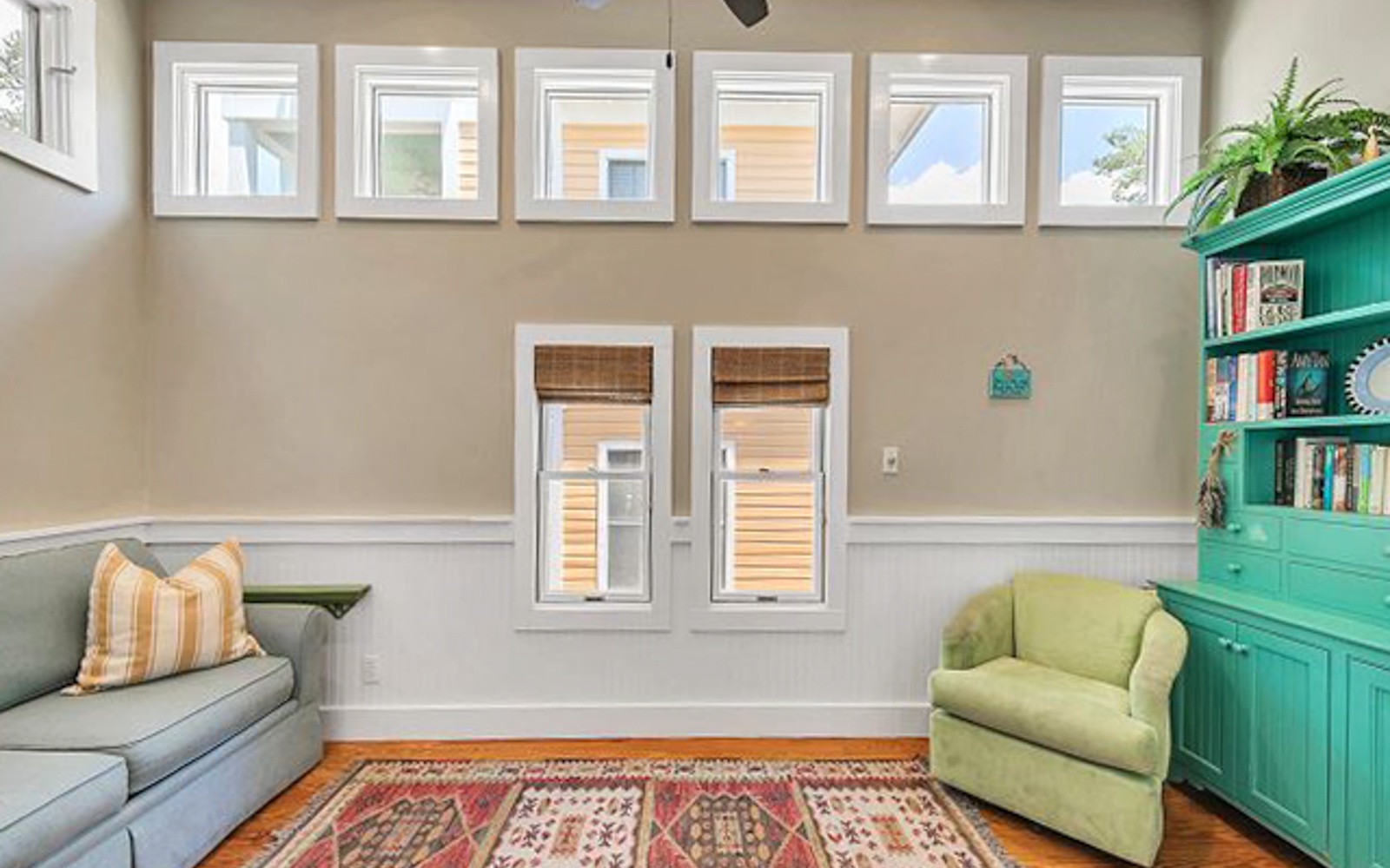 Settle into your bright living space with cozy seating, warm wood floors, and a vibrant bookshelf for quiet moments.