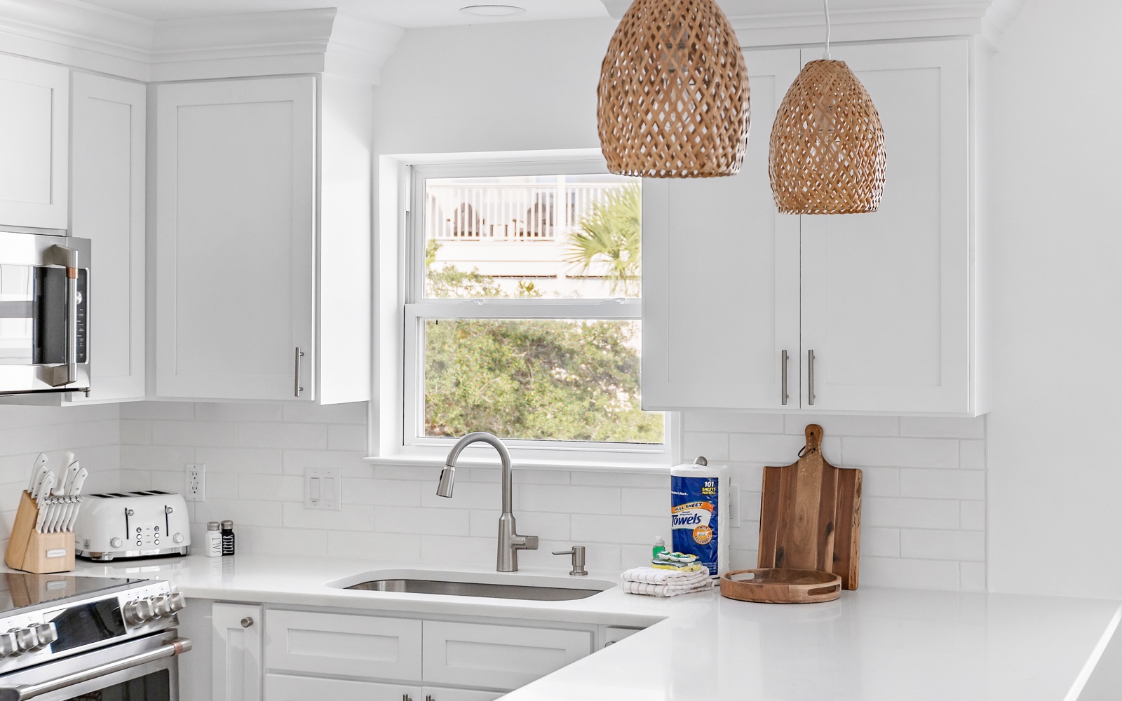 Your bright modern kitchen awaits with sleek white cabinets, quartz counters, and charming woven pendant lights creating the perfect cooking sanctuary.