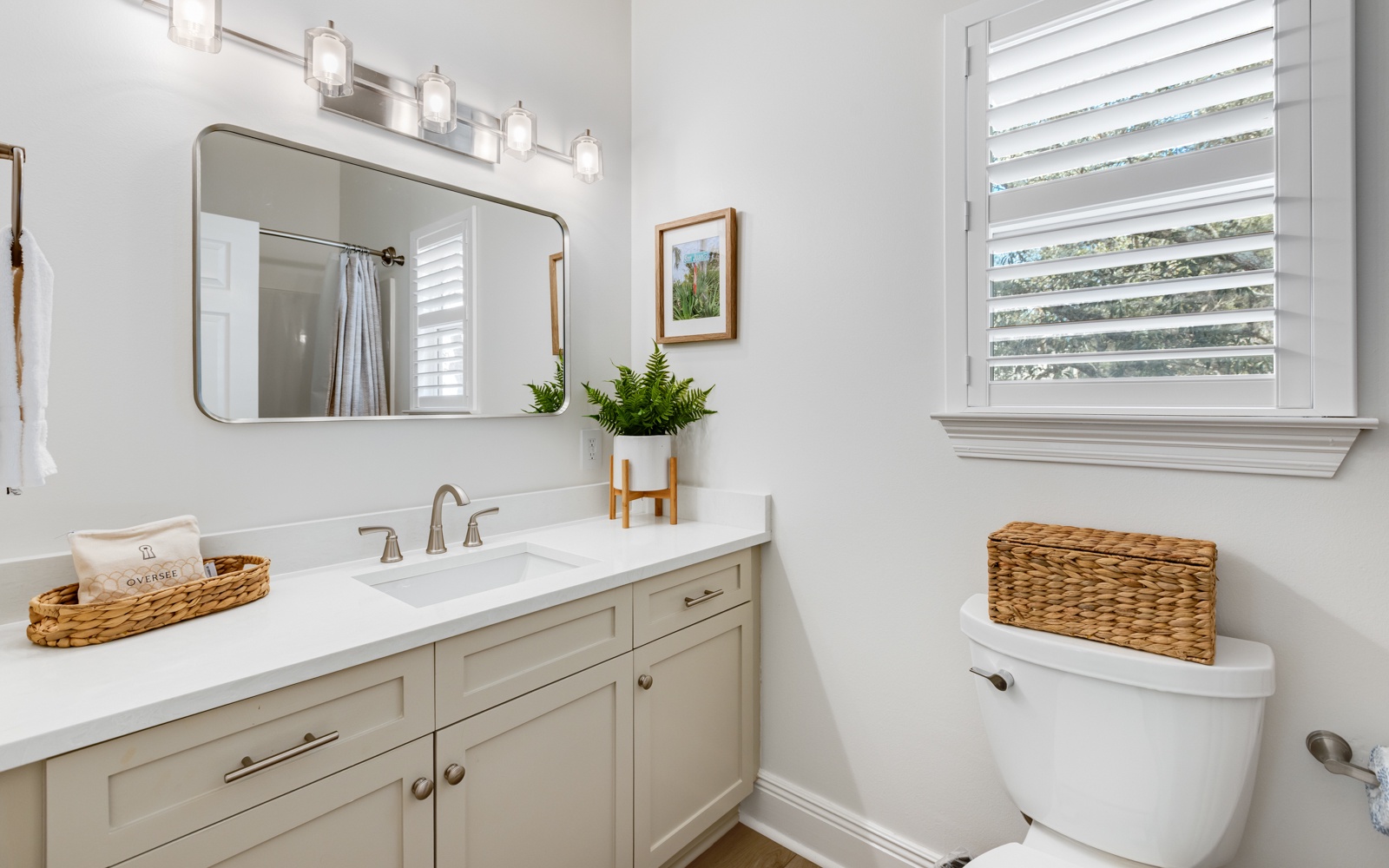 Your pristine bathroom features warm touches like woven baskets and fresh greenery, creating a spa-like retreat for your daily routine.