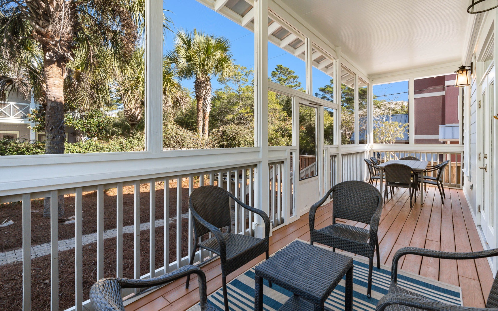 Your screened porch offers peaceful moments with wicker seating and tropical palm views through tall windows.