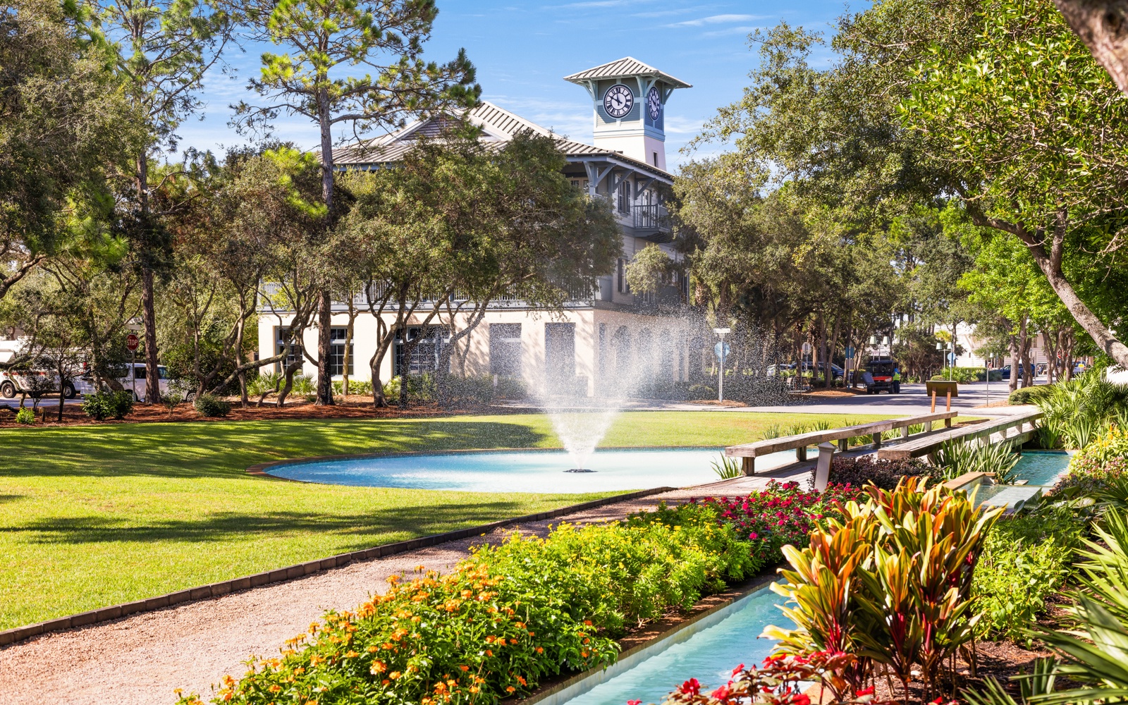 Charming town square with clock tower, landscaped gardens, and water feature creates a picturesque neighborhood setting.