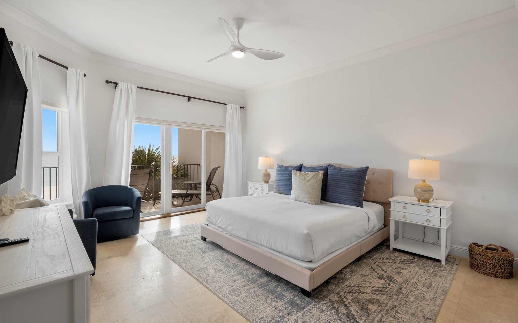 Unwind in your serene bedroom with coastal blue accents, plush bedding, and private balcony access for morning coffee or sunset views.
