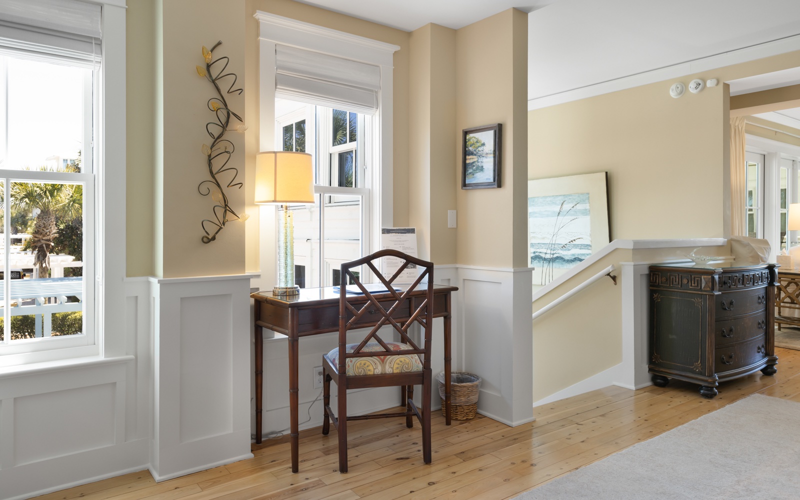 Settle into your charming writing nook with coastal artwork and warm natural light streaming through windows.