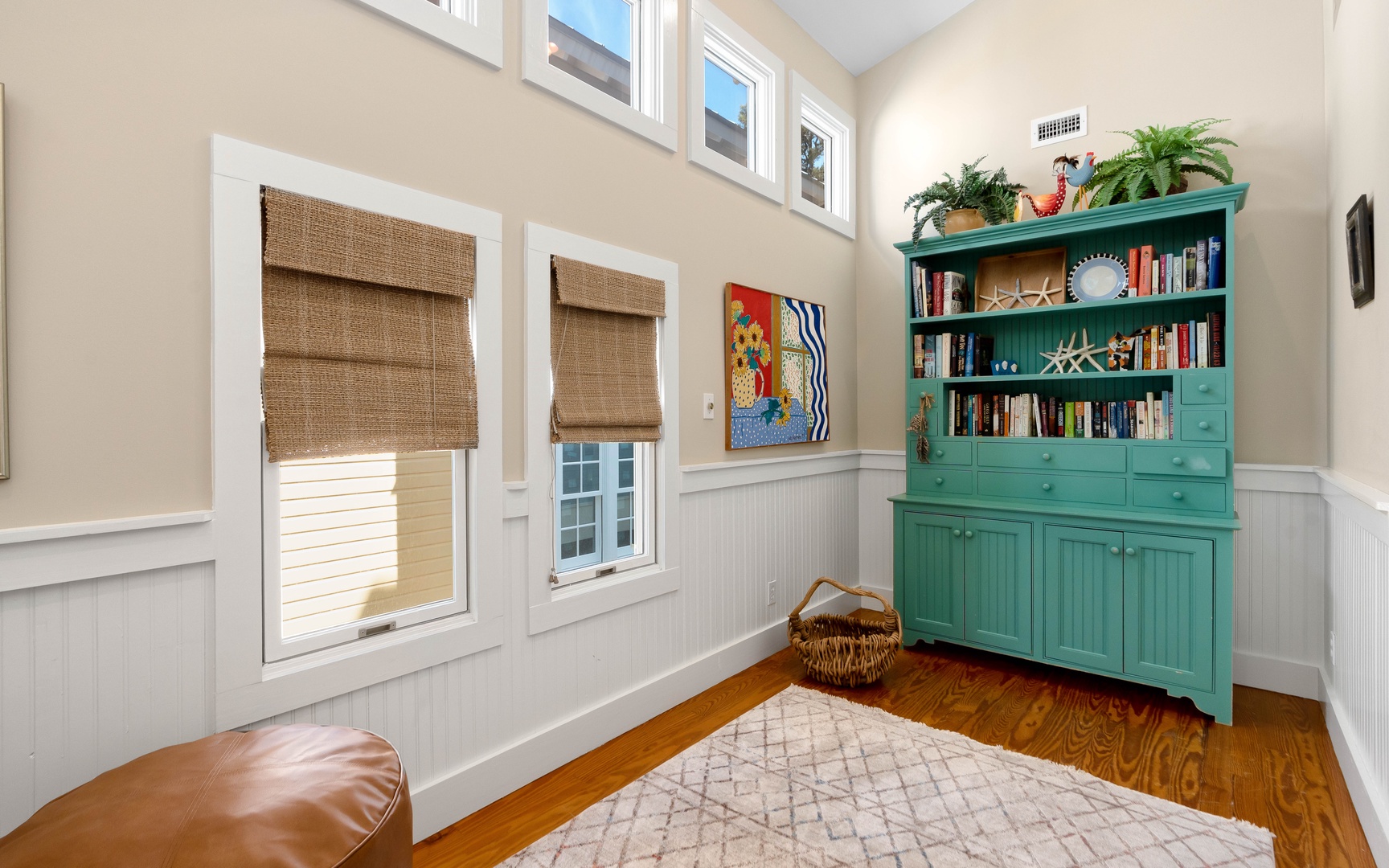 Curl up in your cozy reading nook with rich hardwood floors, charming wainscoting, and a stunning turquoise bookcase filled with stories.