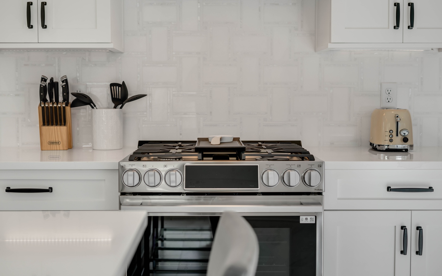 Cook your favorite meals in this modern kitchen featuring a professional gas range and sleek marble countertops.