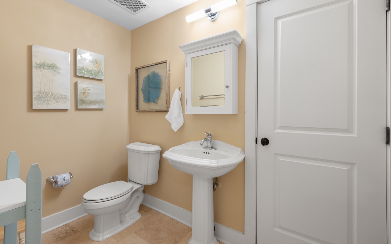 Your private powder room offers comfort and style with warm colors, elegant fixtures, and coastal artwork creating a welcoming space.