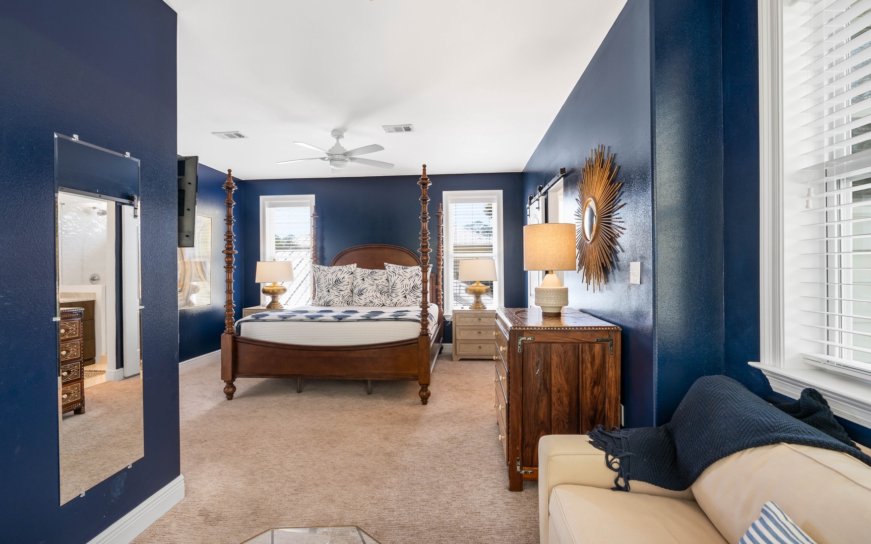 Unwind in your elegant navy sanctuary featuring a four-poster bed and warm wood furnishings for peaceful nights.
