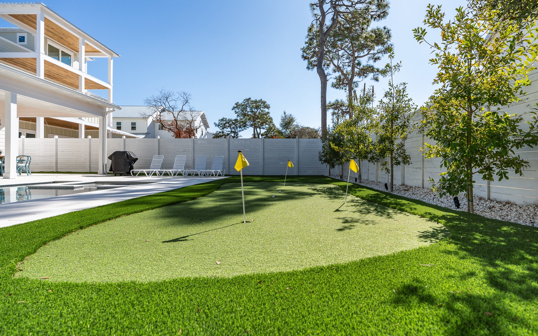 Perfect your putting game on your private artificial green, surrounded by lush landscaping and modern amenities in this bright backyard oasis.