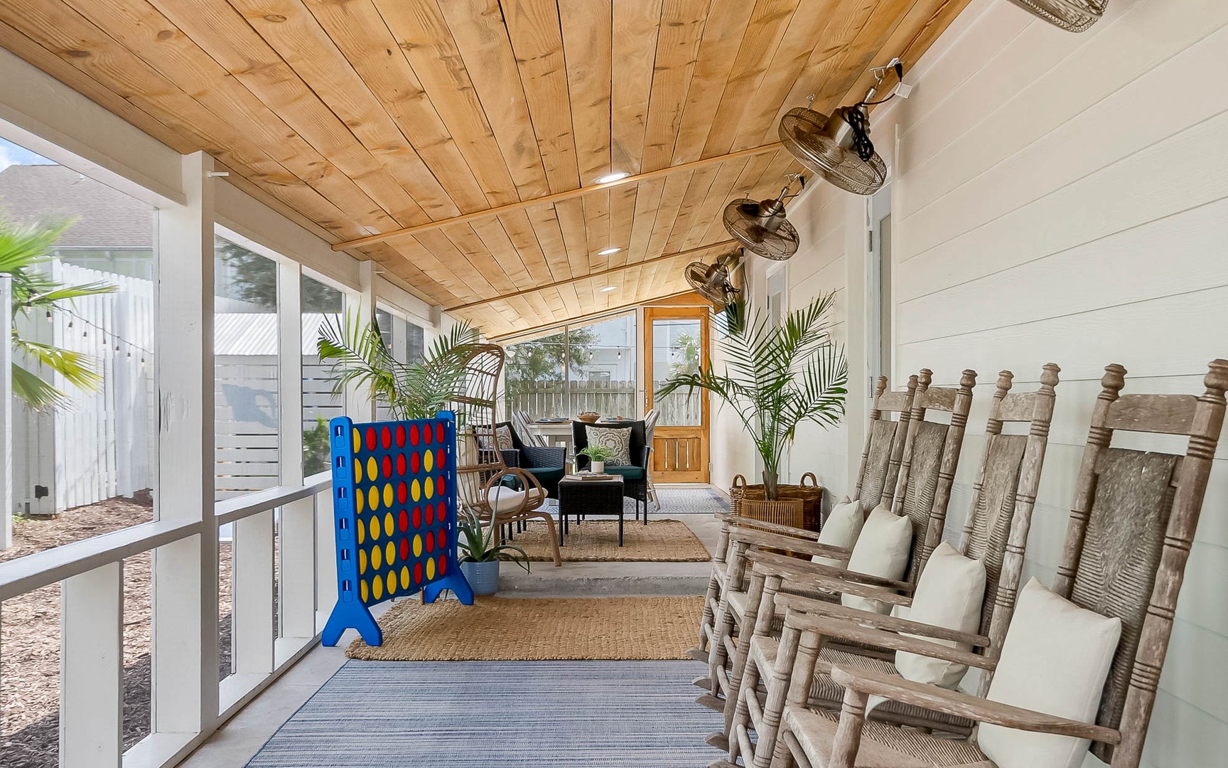 Your screened porch combines rustic charm with modern comfort—rocking chairs, tropical plants, and games create the perfect retreat.