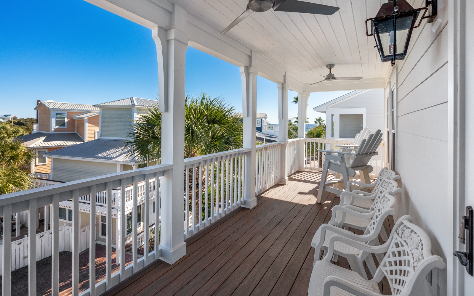 Sip your morning coffee on this covered balcony, watching the coastal breeze sway palm fronds while white chairs invite peaceful moments.