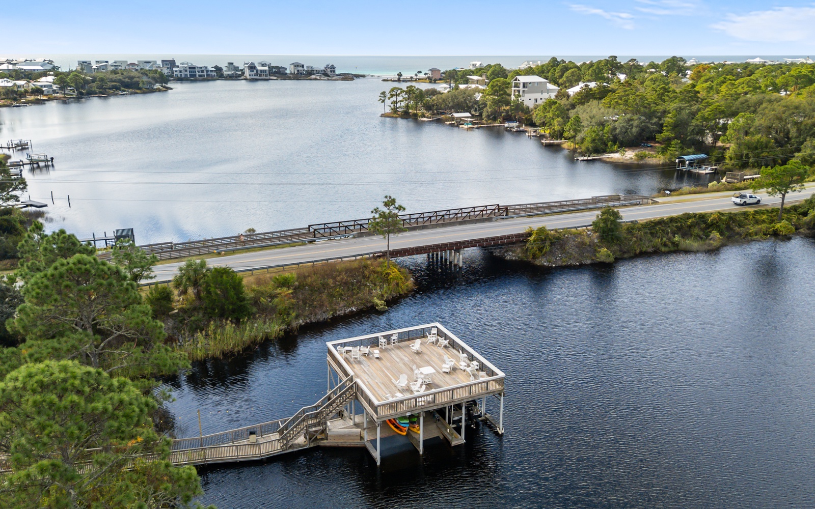 Aerial view of waterfront community with fishing dock, bridge, and residential properties along the peaceful lake.
