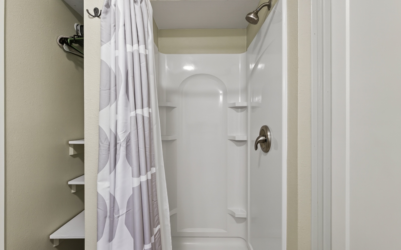 Step into your private shower sanctuary with fresh white linens, convenient corner shelves, and everything ready for your refreshing morning routine.