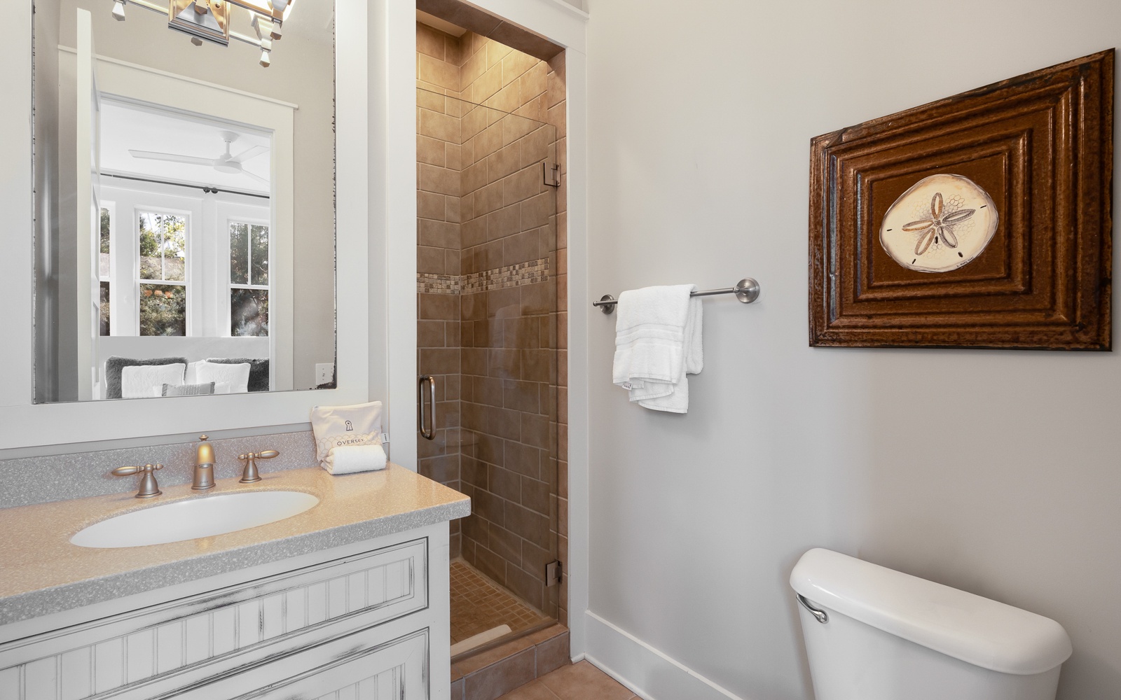 Fresh towels await in your beautifully appointed bathroom, where coastal charm meets modern comfort with elegant tiling and thoughtful touches.