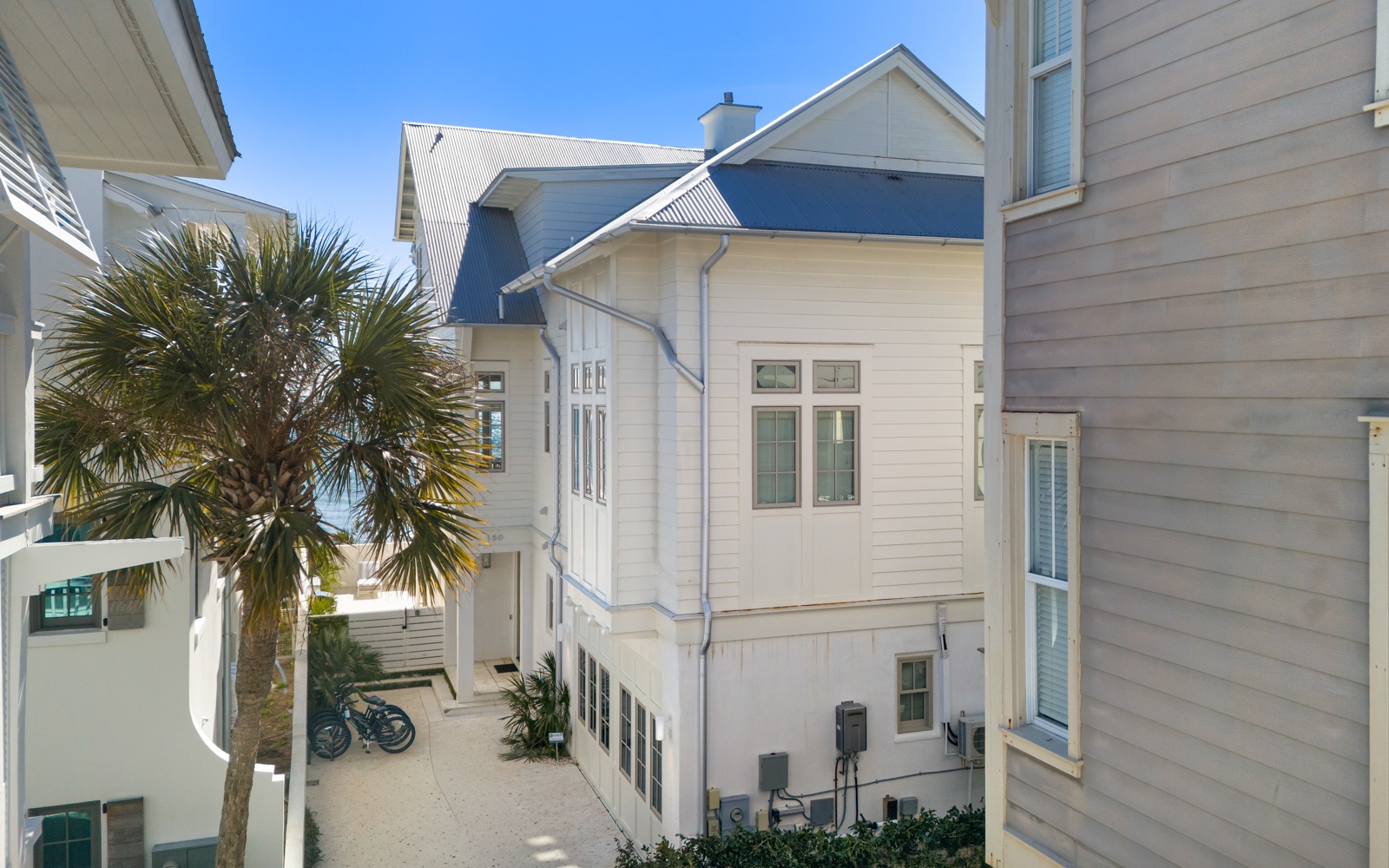 Charming coastal architecture creates a peaceful neighborhood setting with palm trees and blue skies overhead.