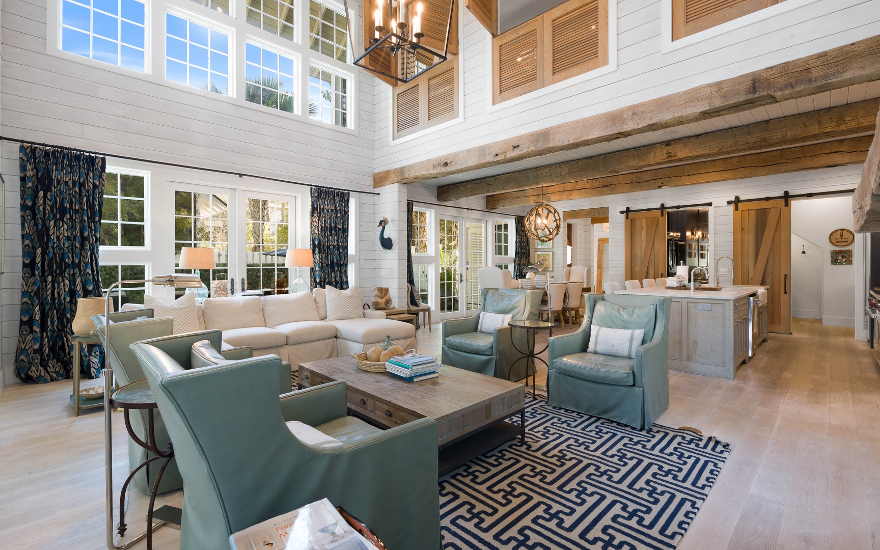 Relax in your spacious open-concept living area featuring soaring ceilings, rustic wooden beams, and comfortable seating perfect for gathering with loved ones.
