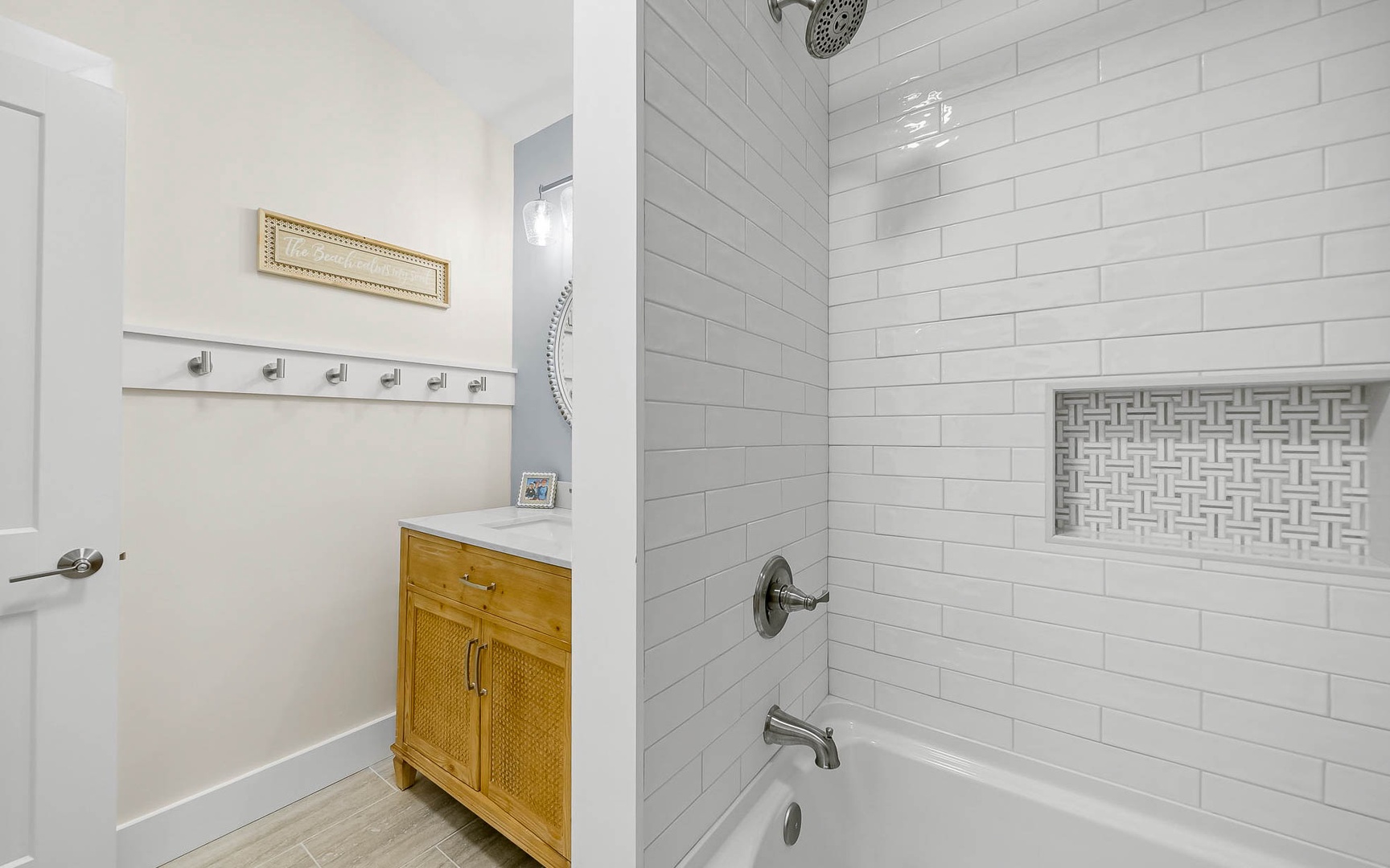 Unwind in your pristine bathroom featuring a luxurious subway-tiled tub-shower combo and charming natural wood vanity for all your essentials.