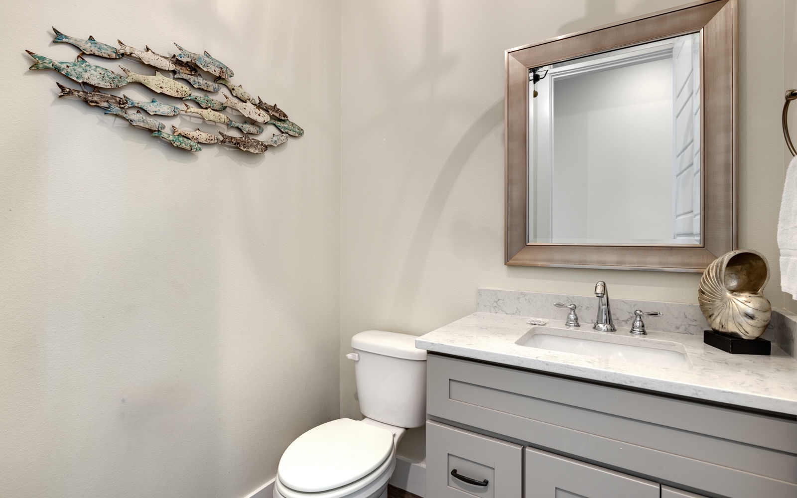 Your elegant powder room features coastal charm with artistic fish decor, marble countertops, and quality fixtures for your comfort.