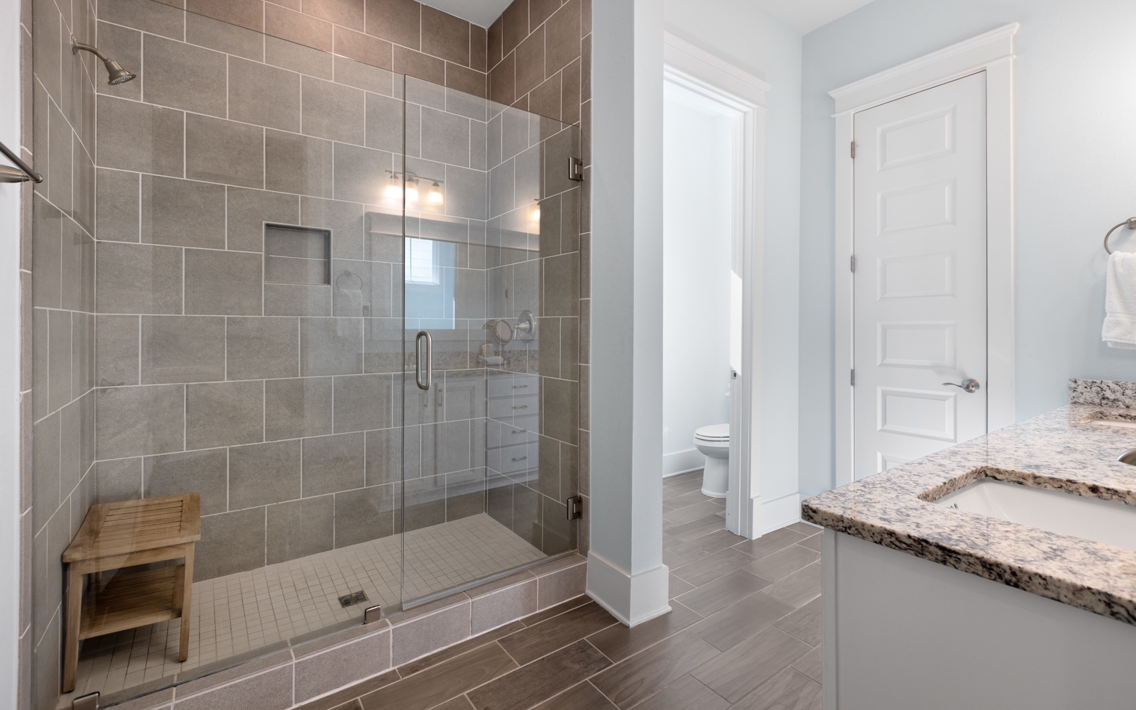 Step into your spa-like sanctuary with a gorgeous walk-in shower featuring elegant gray tiles and warm lighting for ultimate relaxation.