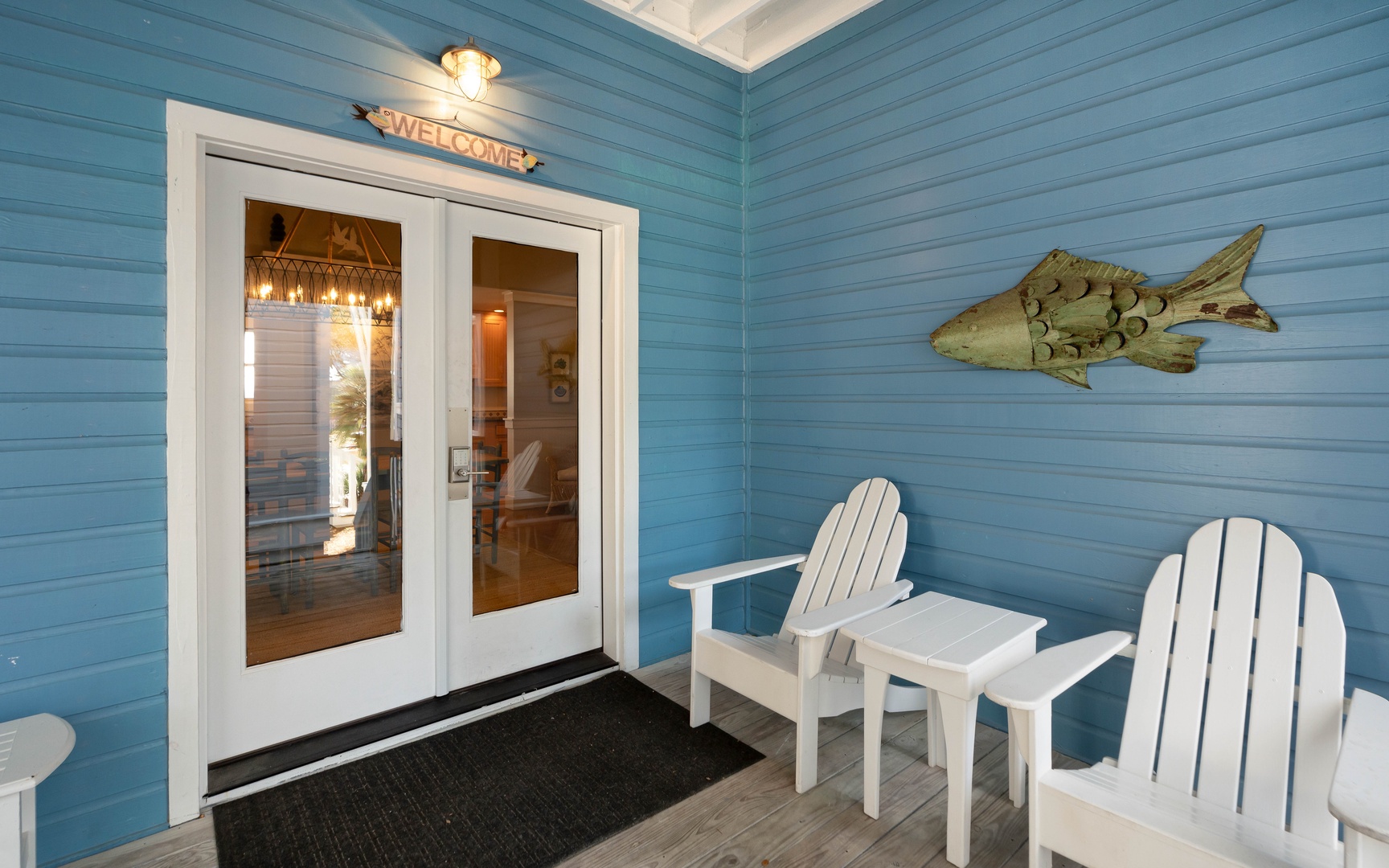 Step into your coastal retreat through welcoming double doors, where beach vibes await with charming Adirondack chairs and nautical touches.