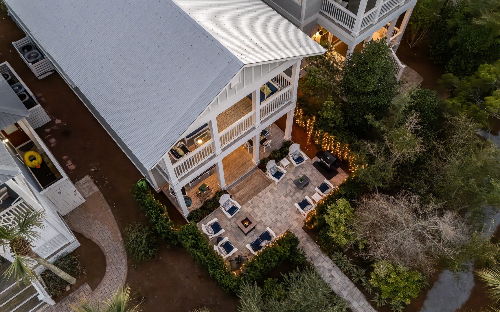 Stunning aerial view of a beautifully designed vacation rental property featuring a spacious outdoor patio with comfortable seating and lush landscaping.