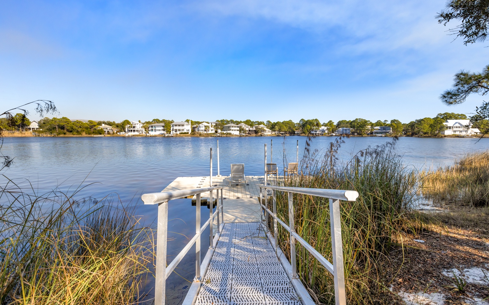Private dock extending into calm lake waters, surrounded by waterfront homes and natural vegetation.