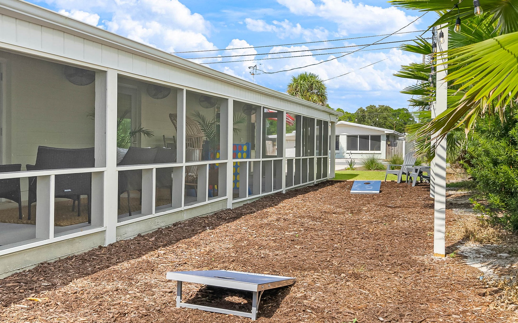 Modern property featuring screened outdoor areas with tropical landscaping and palm trees in a peaceful residential setting.