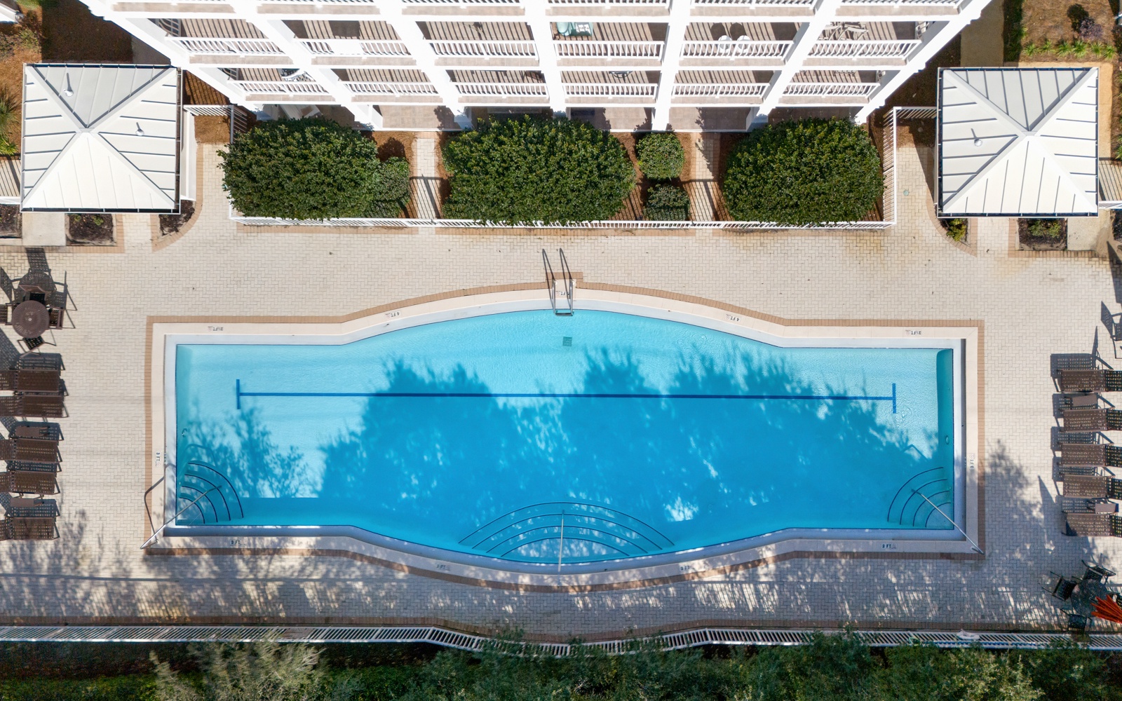 Aerial view reveals the property's stunning swimming pool surrounded by sun loungers and lush greenery, creating an inviting outdoor oasis.