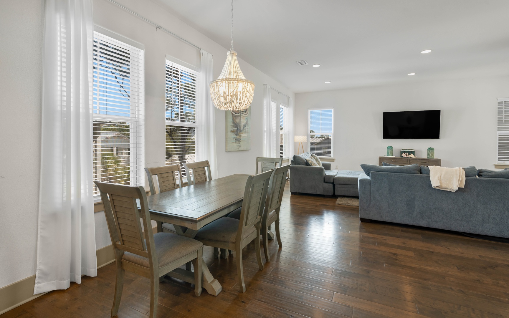 Relax in your bright, modern living space with rich hardwood floors, elegant chandelier, and comfortable furnishings perfect for unwinding together.