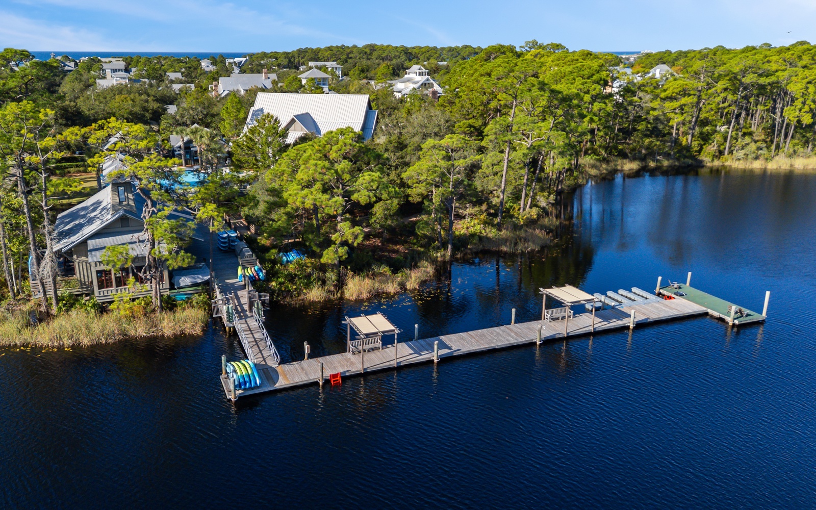 Aerial view of waterfront vacation homes nestled among lush trees with private dock extending into pristine lake waters.