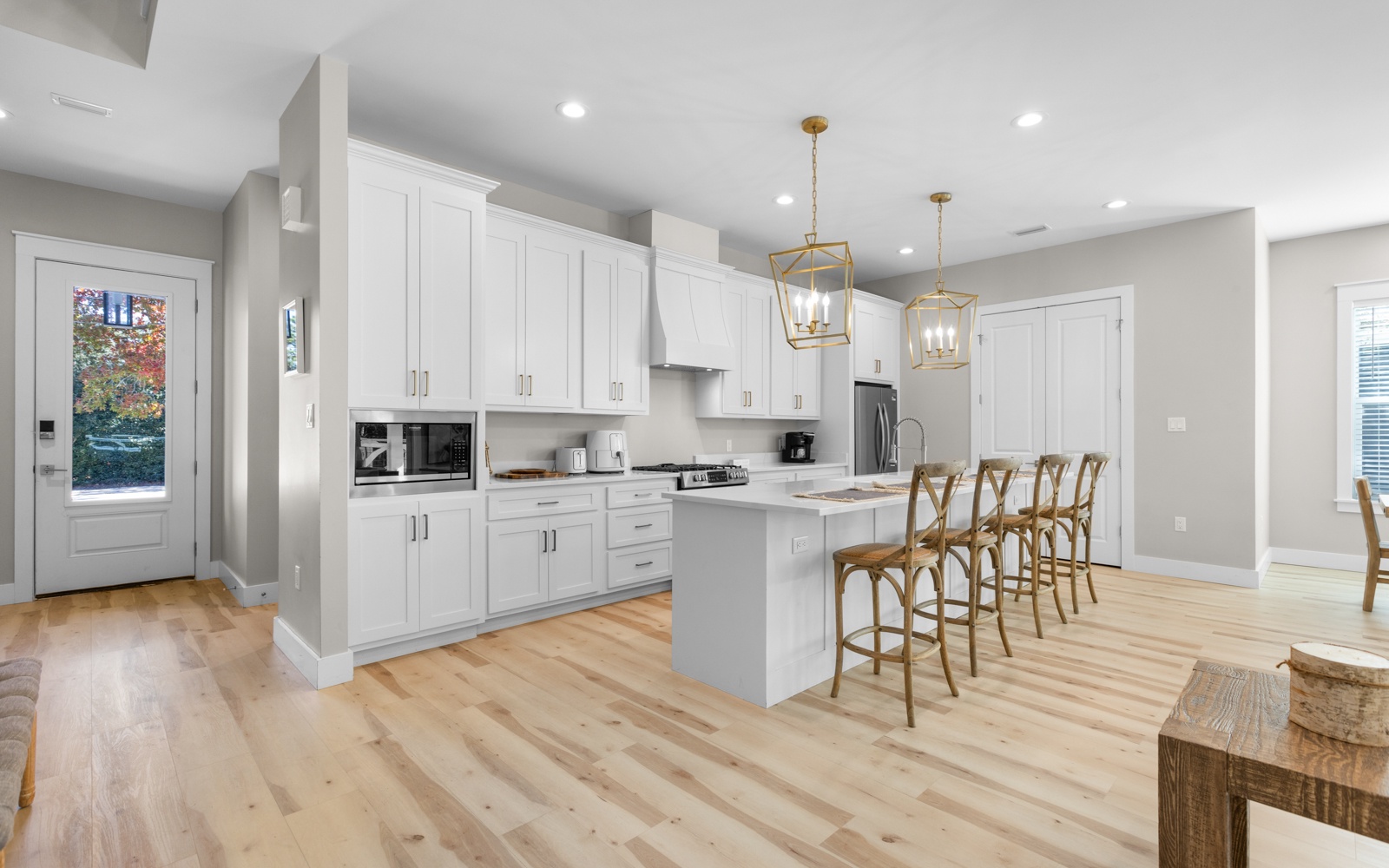 You'll love cooking in this bright, modern kitchen featuring pristine white cabinets, elegant brass pendant lights, and a spacious island perfect for gathering.