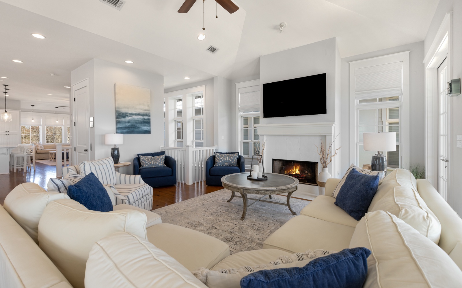 Sink into plush sofas by your crackling fireplace, where navy accents and coastal art create the perfect spot for cozy evening conversations.