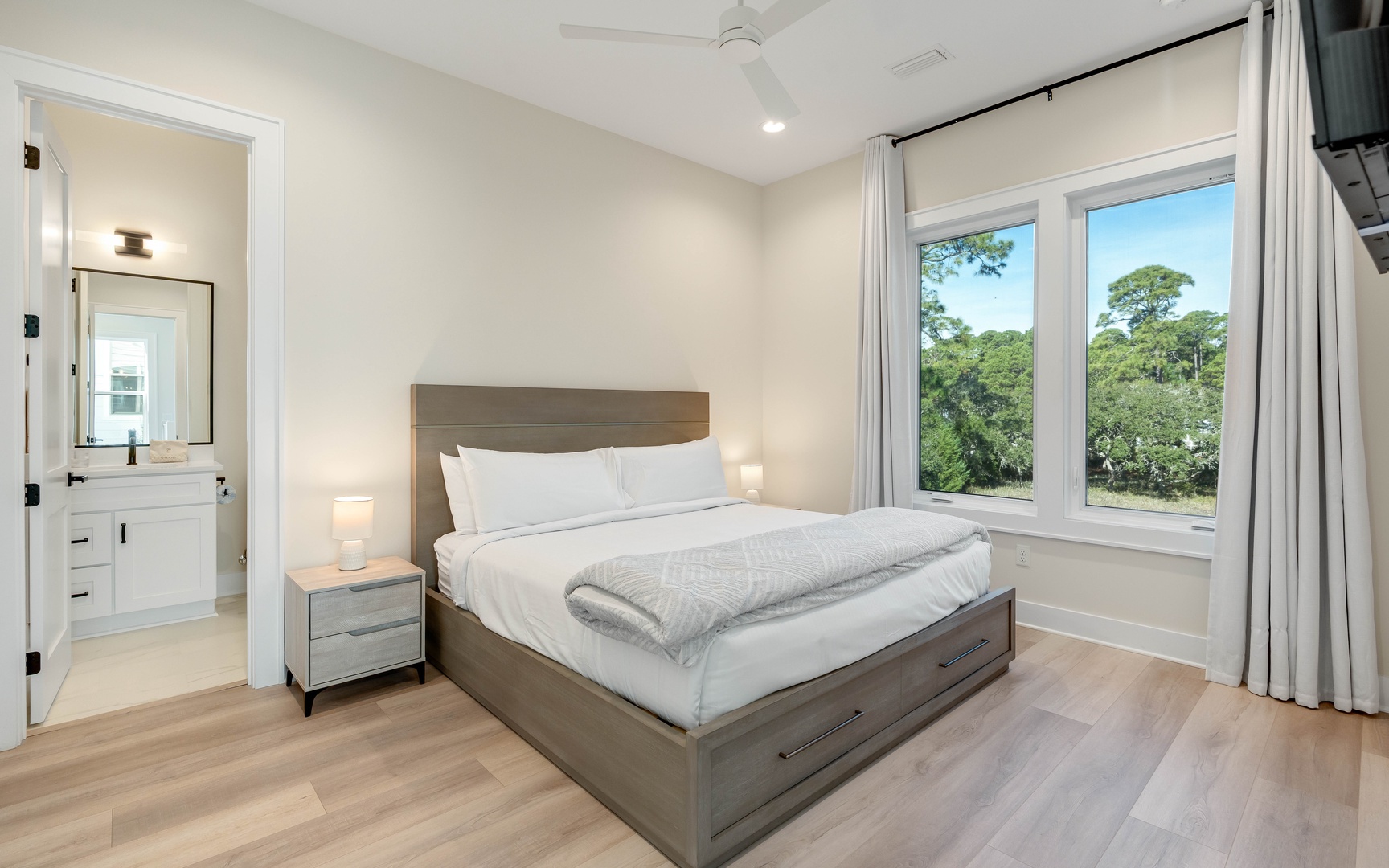 Wake up in your serene bedroom sanctuary with treetop views streaming through large windows, crisp linens awaiting your peaceful retreat.