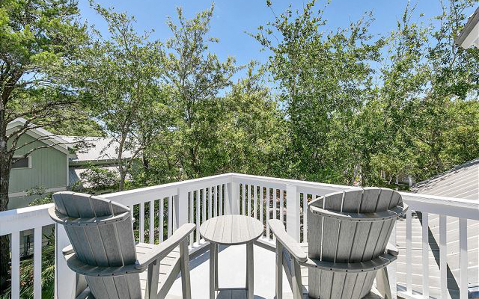 Unwind on your private deck with cozy chairs and table, surrounded by lush greenery and peaceful neighborhood views.